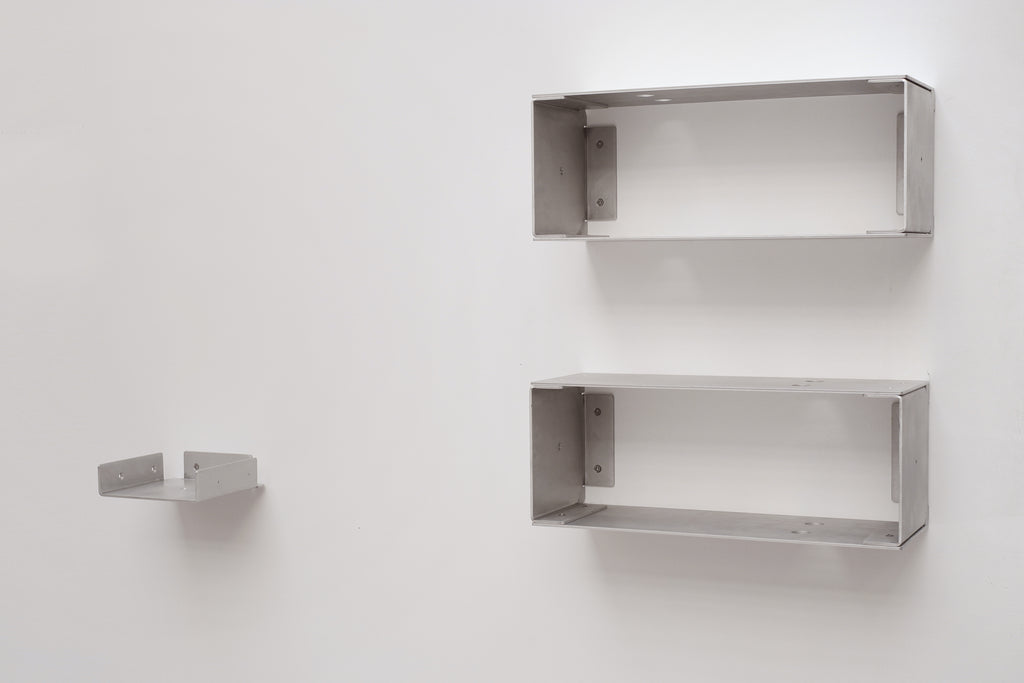 Two metal wall shelves on a white wall