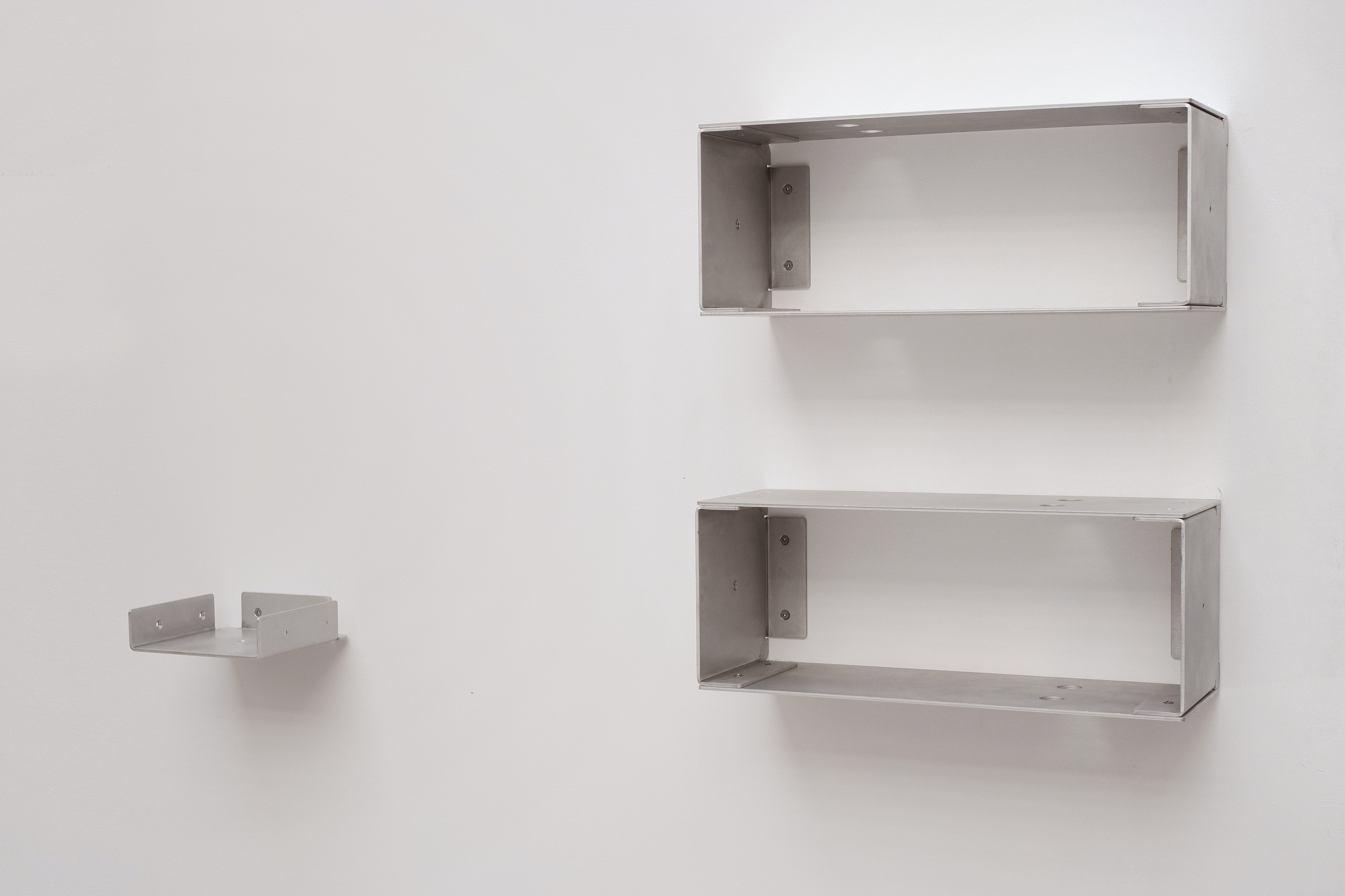 Two metal wall shelves on a white wall