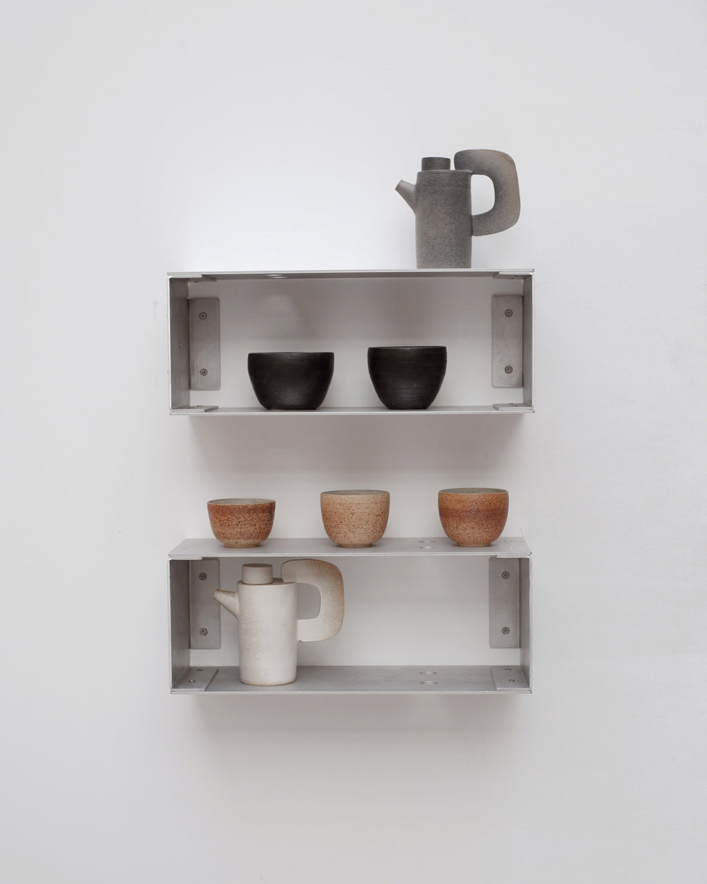 Metal wall shelves with ceramic items against a white wall