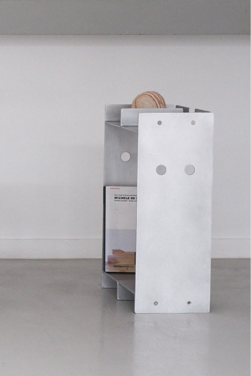 metal bookshelf with round holes against a plain white wall