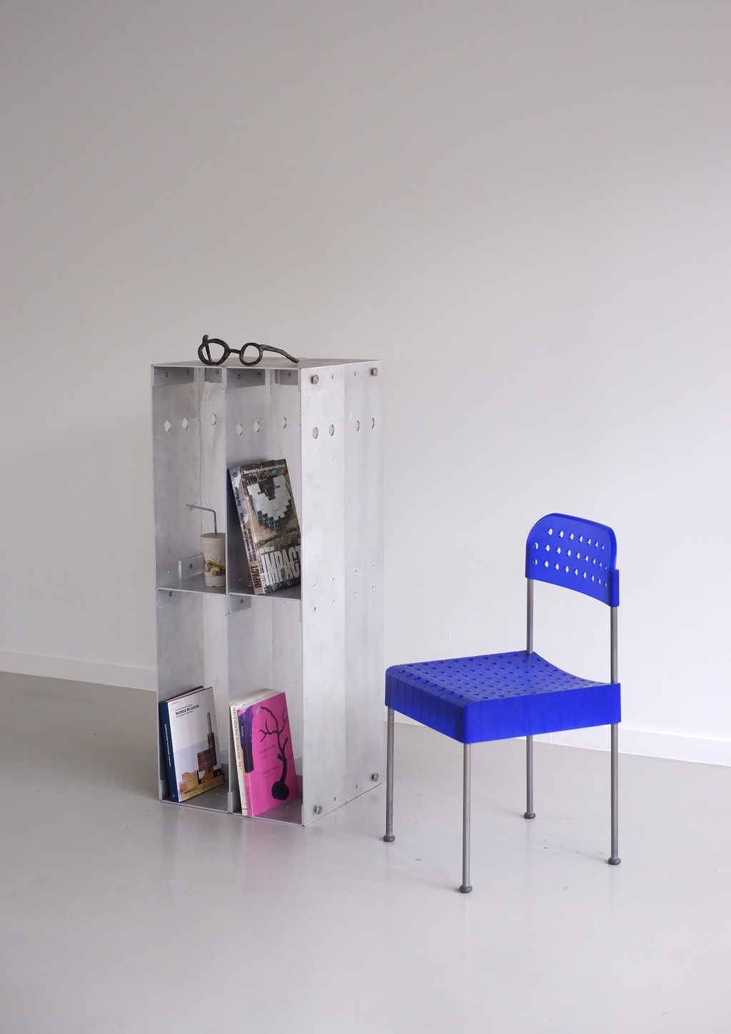 chair next to a metal bookshelf against a white wall