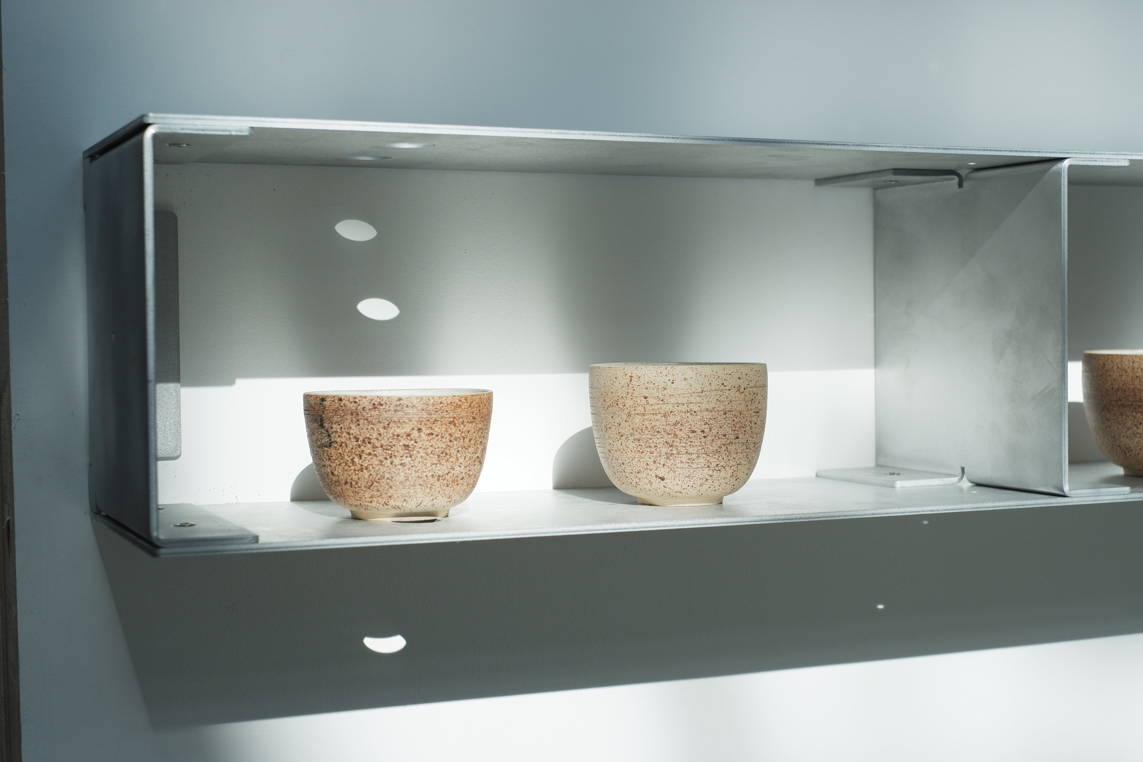 Two ceramic bowls on a shelf with a neutral background