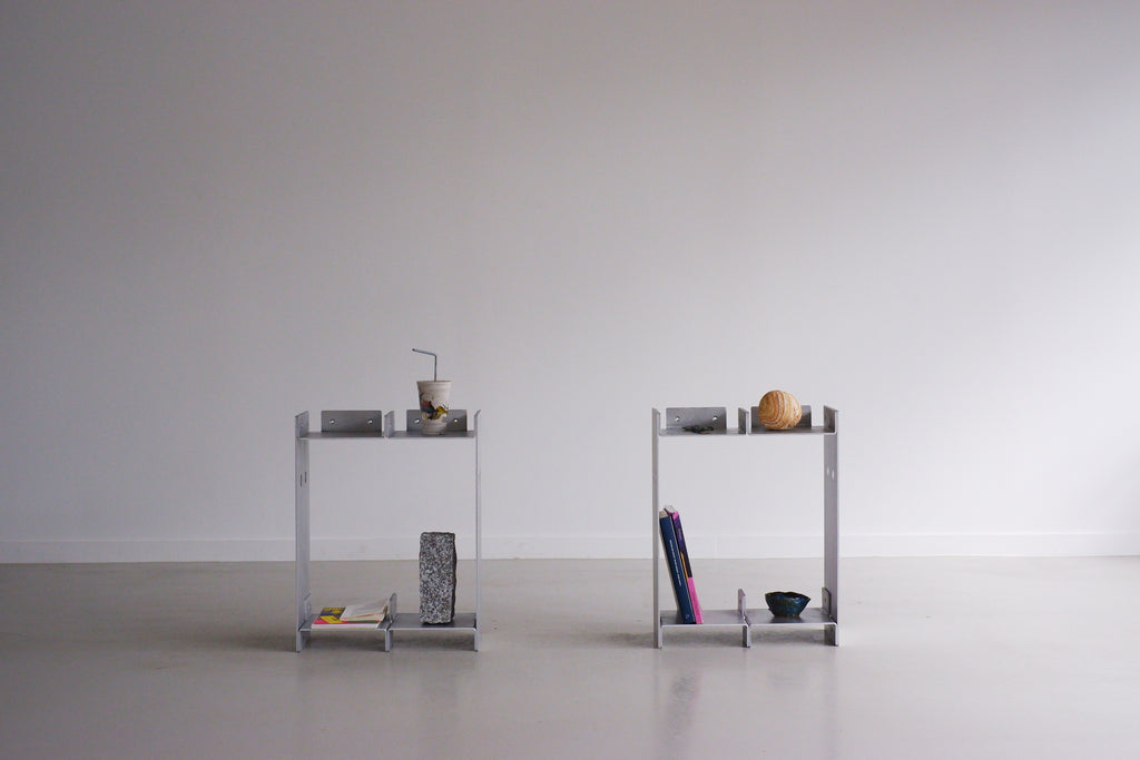 Two small metal shelves with various items on a plain background