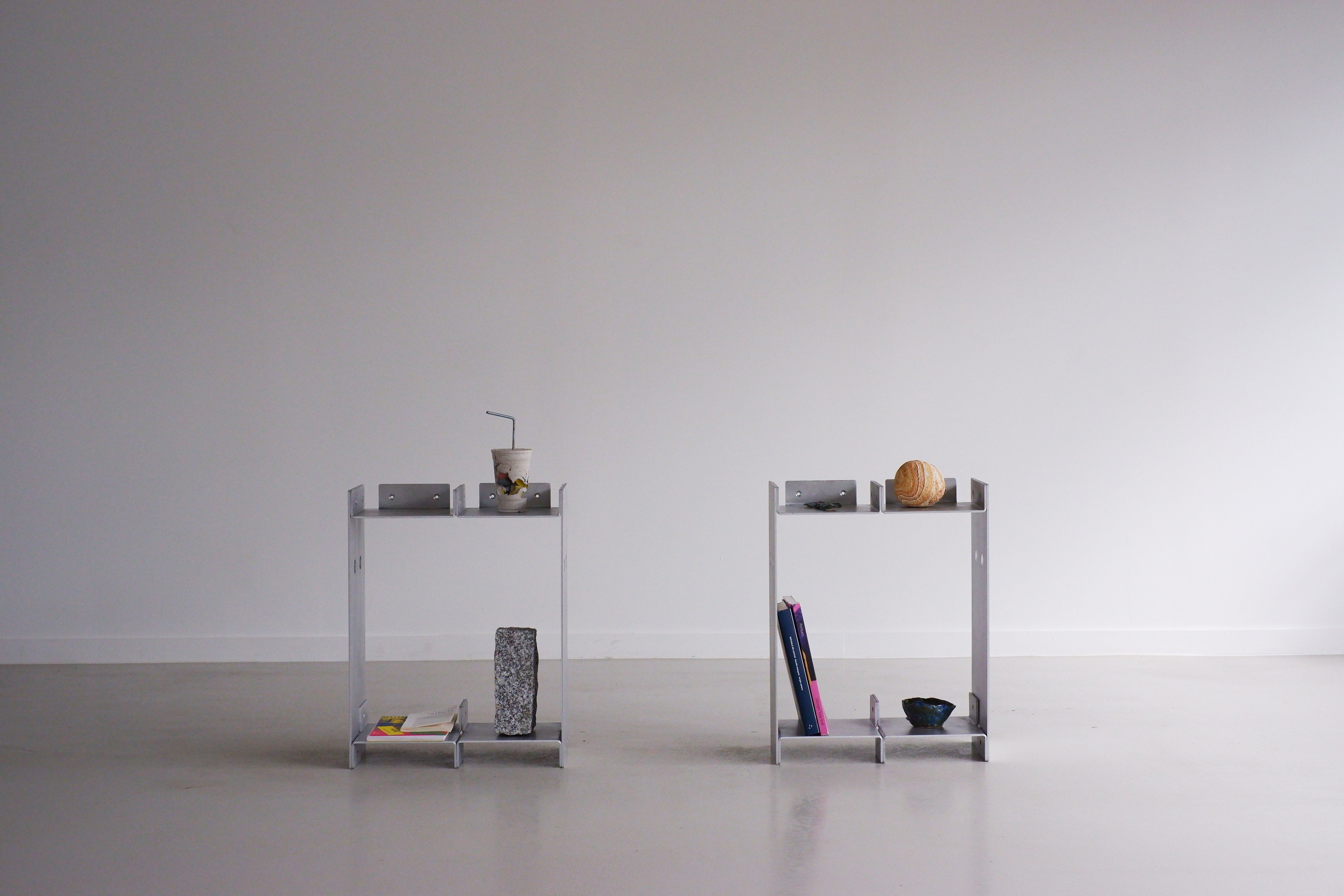 Two small metal shelves with various items on a plain background