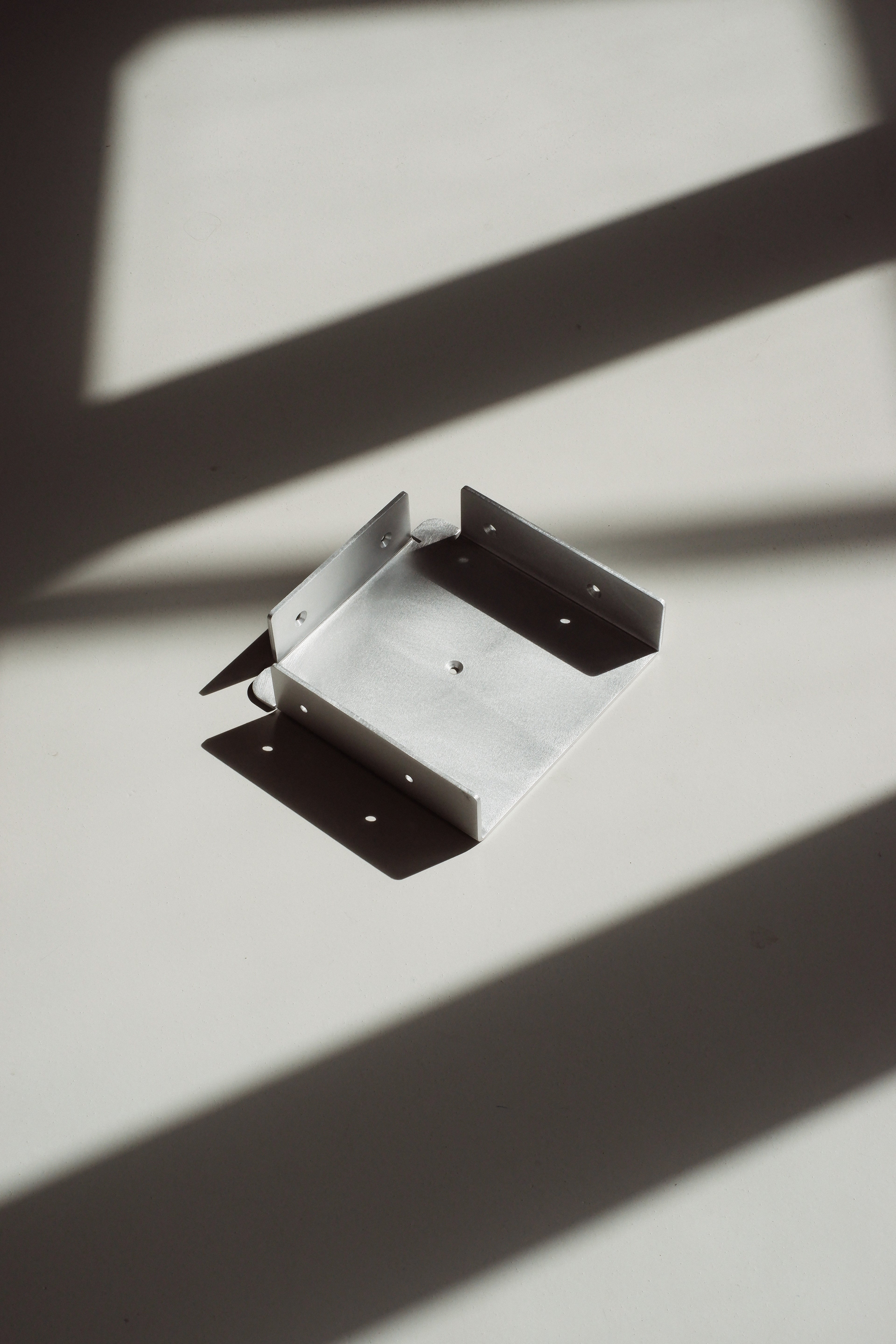 Metal bracket on a white surface with shadows