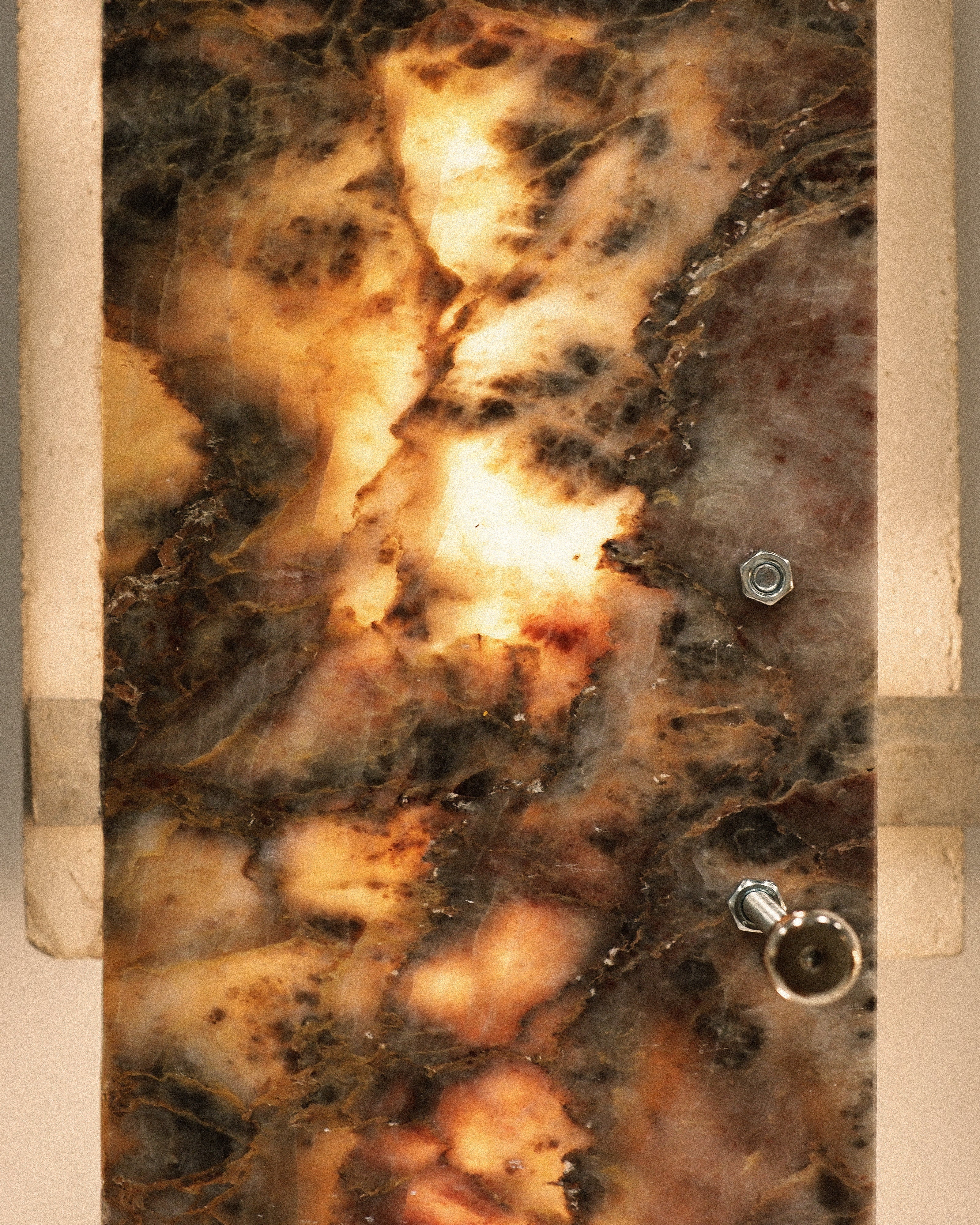 Marble-patterned stone with embedded metal bolts on a blurred background