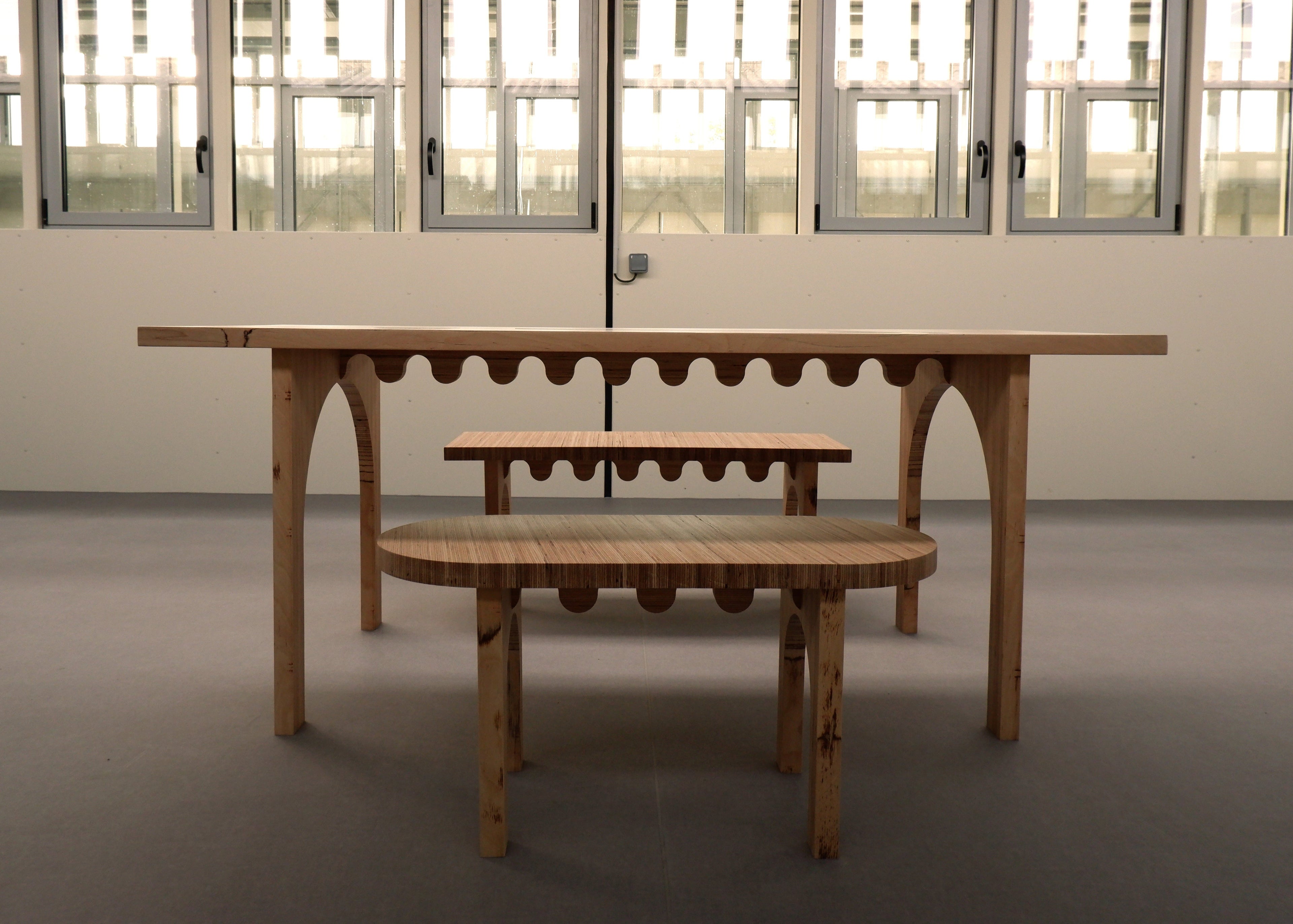 Wooden table and benches in a room with large windows.