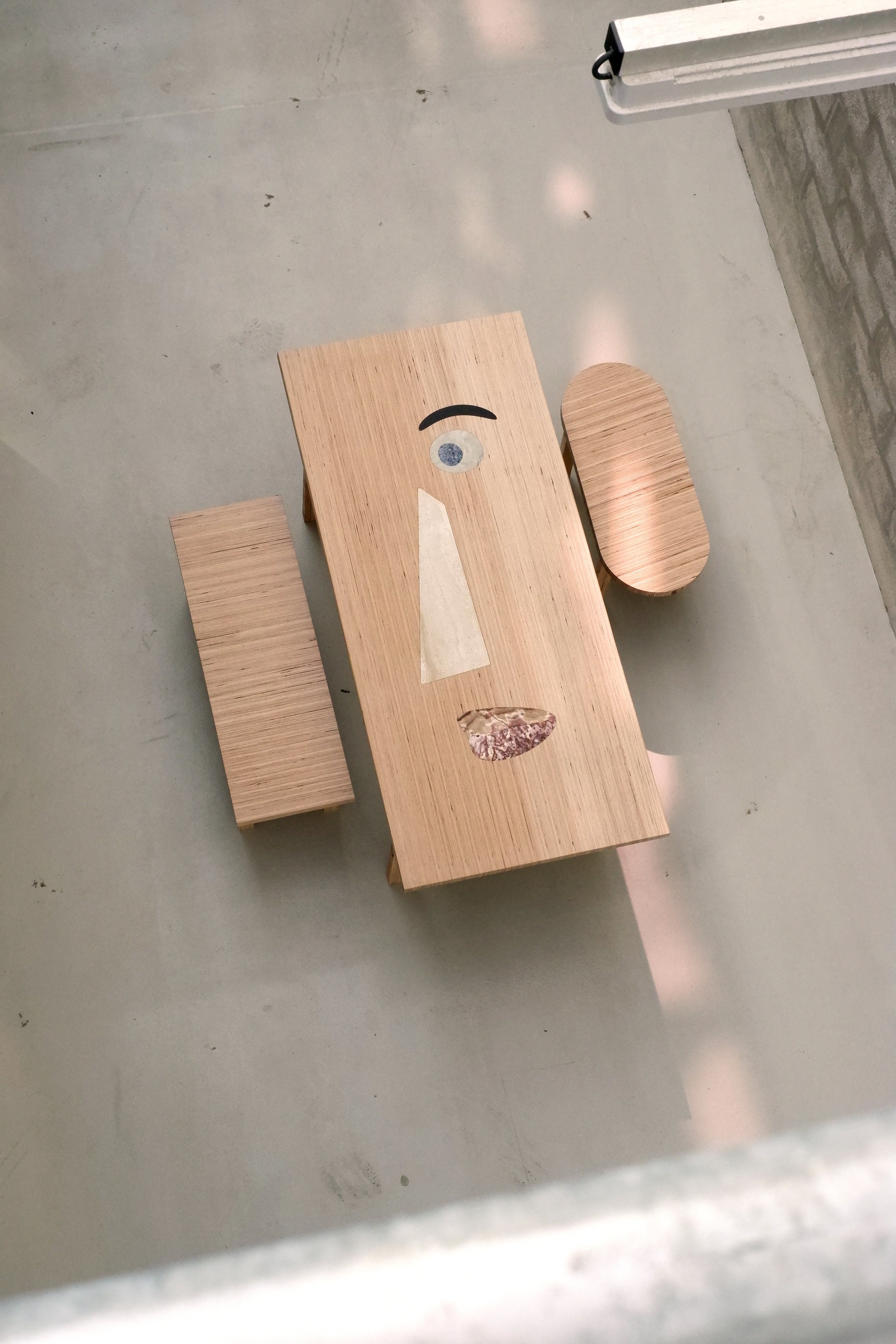 Wooden face-shaped blocks with facial features on a reflective surface