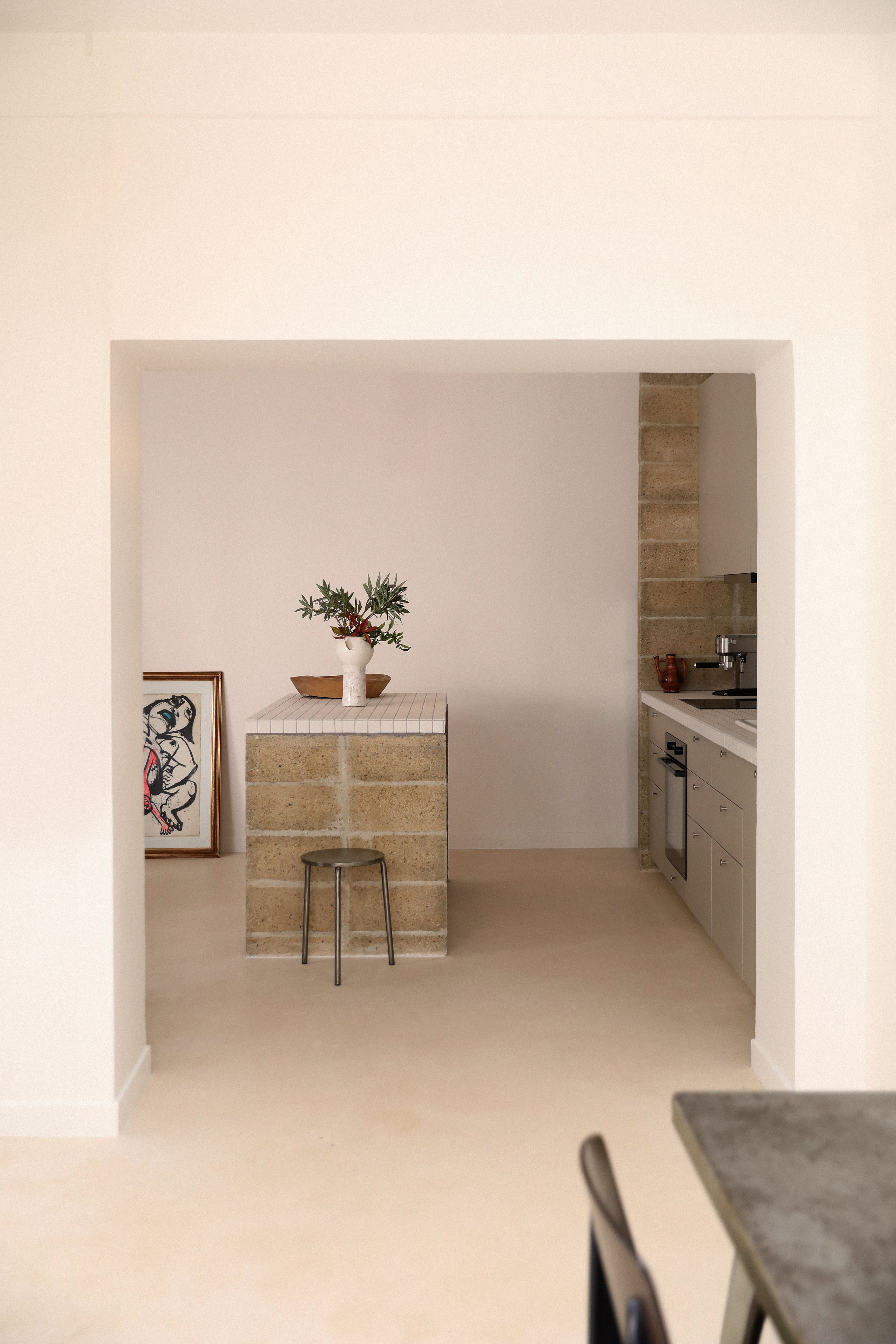 Modern kitchen with a small table and plant, framed picture on the wall.